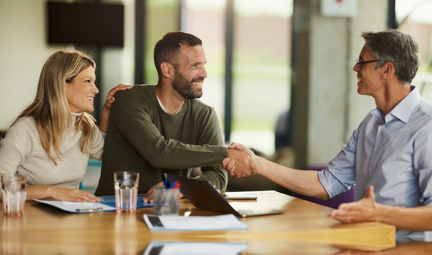 Coworkers speaking to eachother and shaking hands in the office.